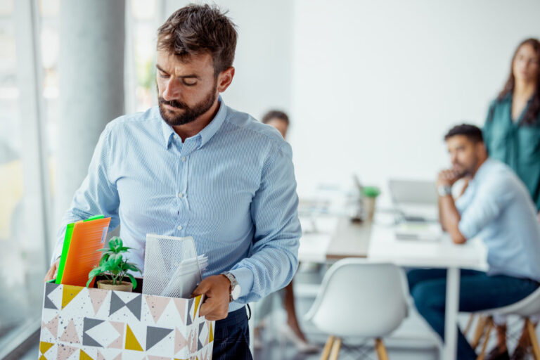 Ein Mann verlässt ein Büro mit seinen Sachen in einer Schachtel